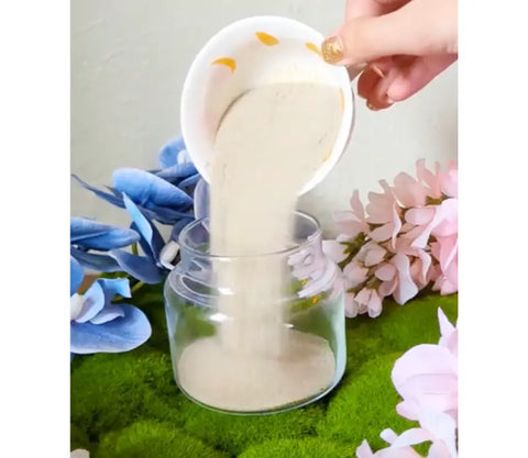 Pouring beige powder into a clear glass jar for a Beltane spell jar ritual
