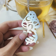 Video showcasing the Herbal Alchemy tea infuser steeping loose leaf tea in a mug while highlighting the mushroom charm and mystical design details.