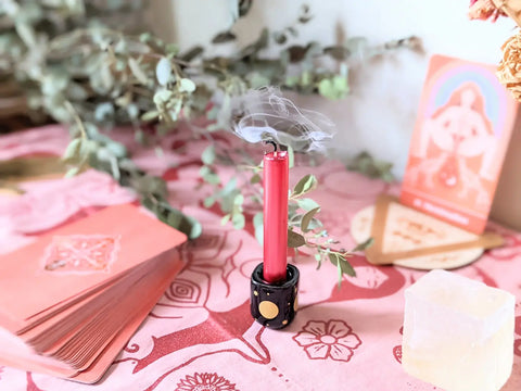 Smoking red ritual candle in a black and gold holder for Moontime Celebration Ritual