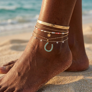 Turquoise horseshoe charm worn as an anklet on the beach.