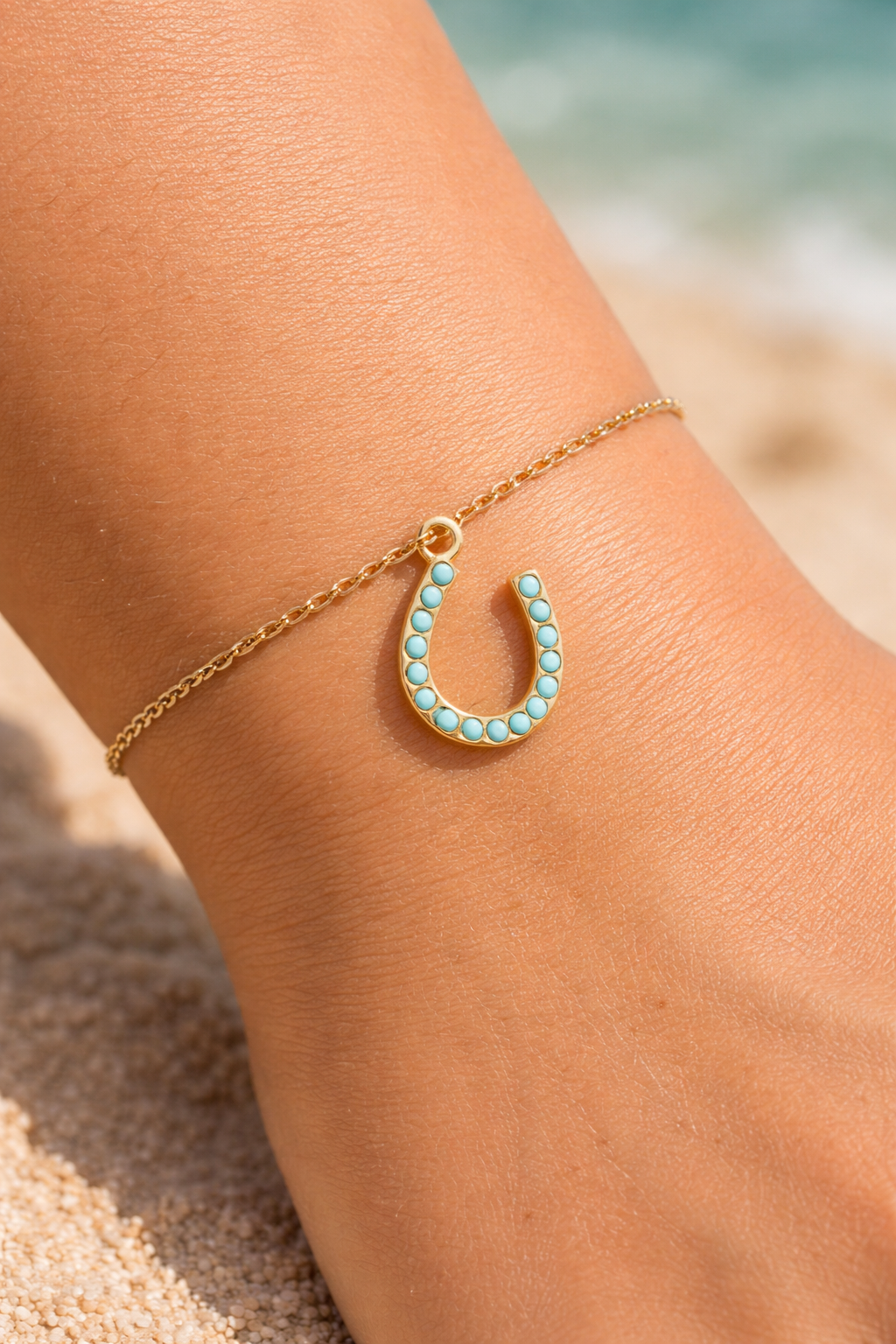 Turquoise horseshoe charm held in hand showing gold charm jewelry detail.