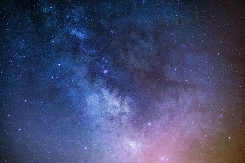Vibrant night sky with stars, nebulae, and the Milky Way galaxy over a peaceful landscape