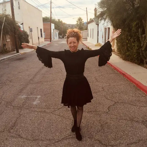 Woman with curly hair in black ruffled cuffs skirt and boots for Goddess Series Isis article