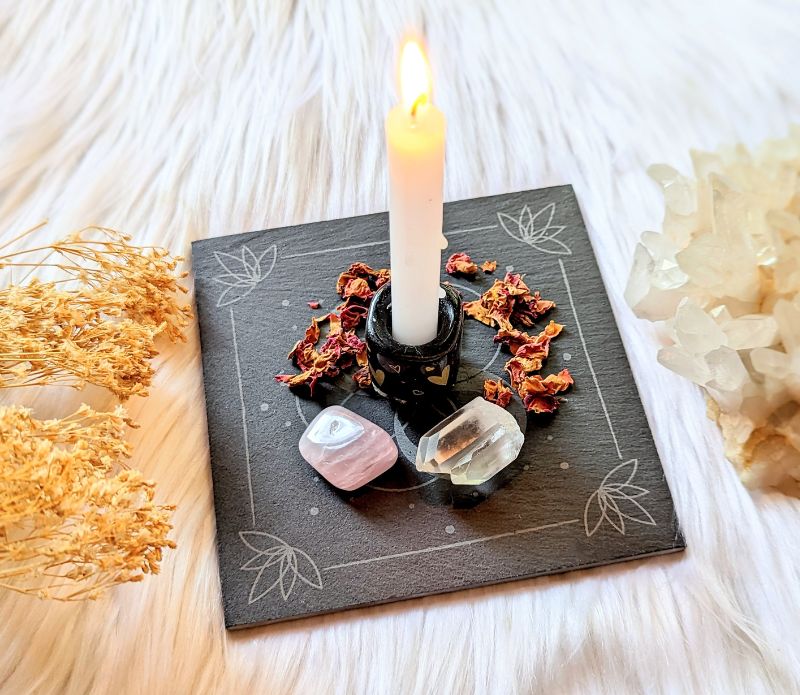 Infinite Magic Altar with a candle, crystals, and herbs arranged in the center. Altar tools available at Goddess Provisions