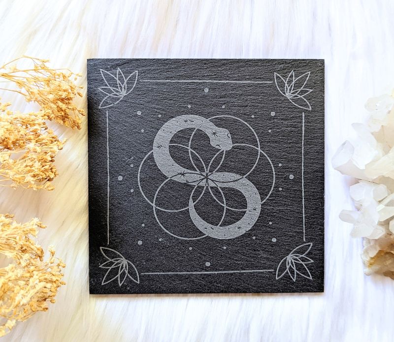 Infinite Magic Altar Tile with a serpent image in the centre and flowers in the corners  on a cloth background. Available at Goddess Provisions