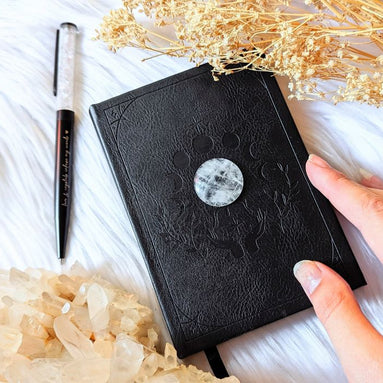 A5 celestial journal made from recycled paper, with 120 lined pages and embossed moon phases design on black vegan leather. Perfect for magical moments and daily to-dos.