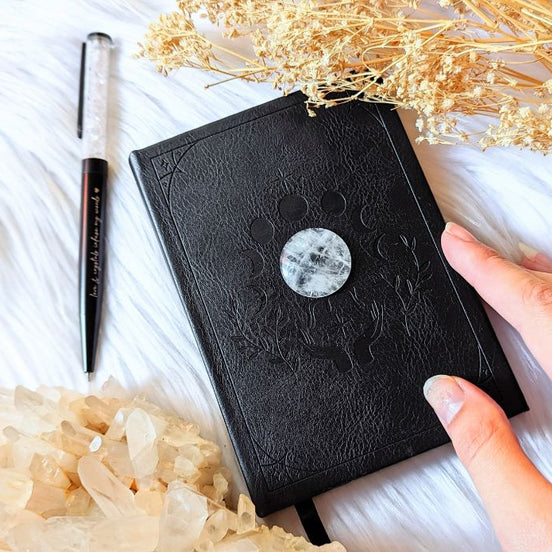 A5 celestial journal made from recycled paper, with 120 lined pages and embossed moon phases design on black vegan leather. Perfect for magical moments and daily to-dos.